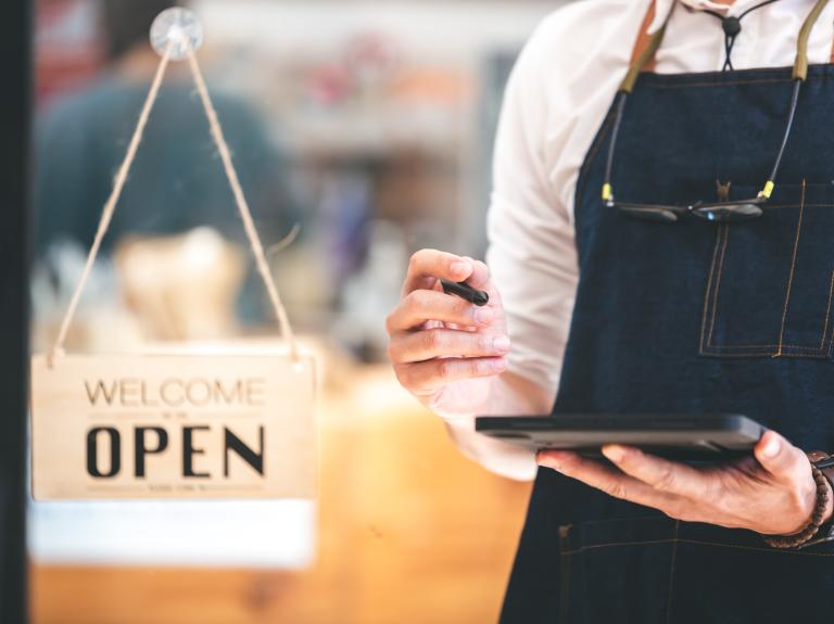 A business owner uses a tablet to prepare for opening their shop.