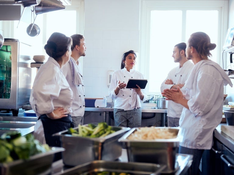 Chefs in white uniforms standing together in a bustling kitchen, ready to prepare delicious meals.
