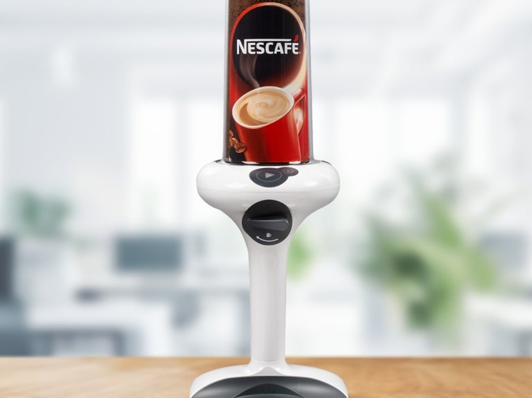A coffee machine with a steaming cup of coffee placed on top, showcasing its sleek design and functionality.