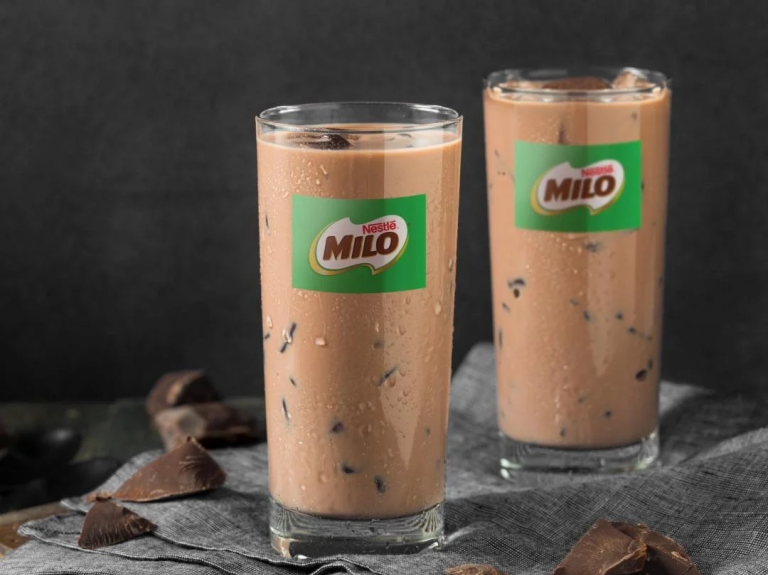 Two glasses filled with milk, each adorned with a layer of chocolate, representing a malt beverage delight.