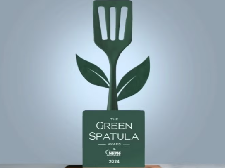 A green spatula award resting on a table, representing achievement in cooking or culinary arts.