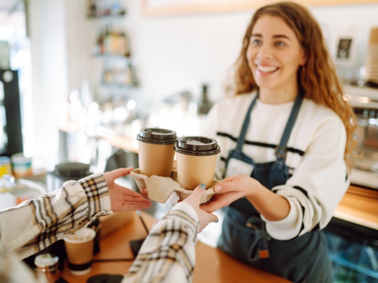 A woman is holding a coffee cup, facing another woman, suggesting a moment of connection and conversation.