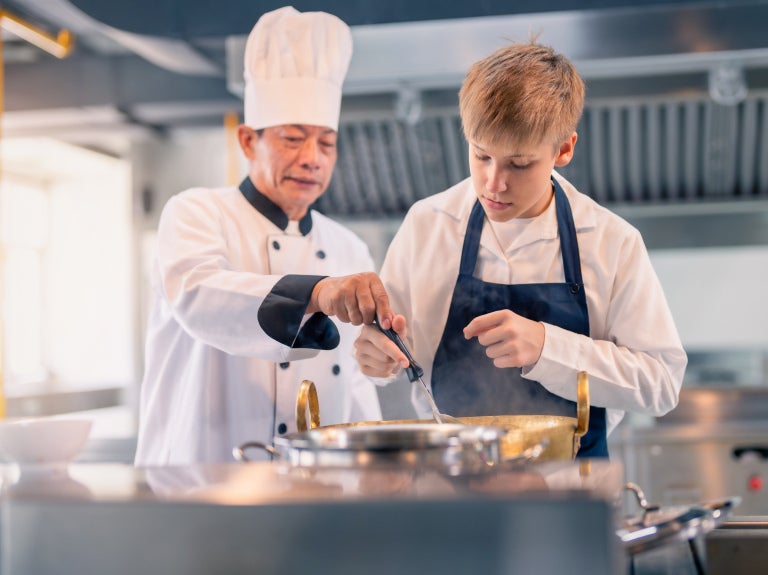 Asian chef teaching cooking to a young chef