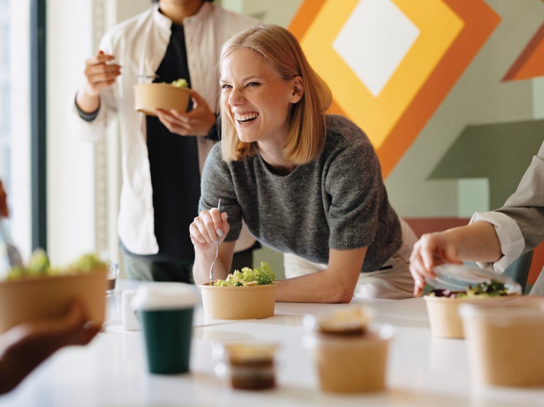 Woman in an office environment having lunch with colleagues