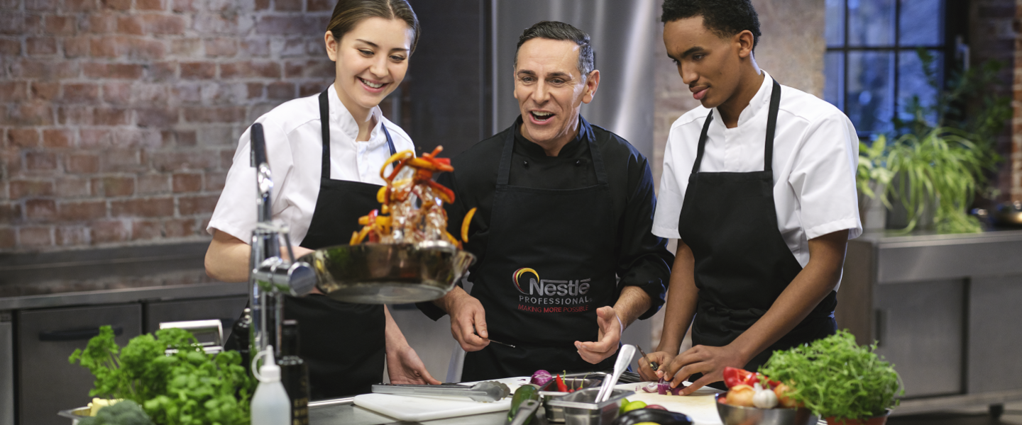 Three smiling chefs joyfully preparing food in a bright kitchen setting.