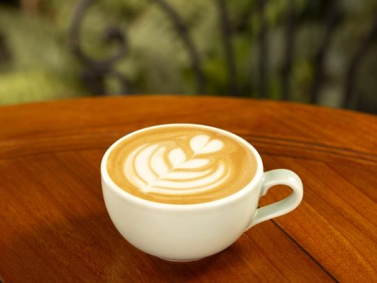 A steaming cup of coffee sits on a rustic wooden table, inviting warmth and comfort.