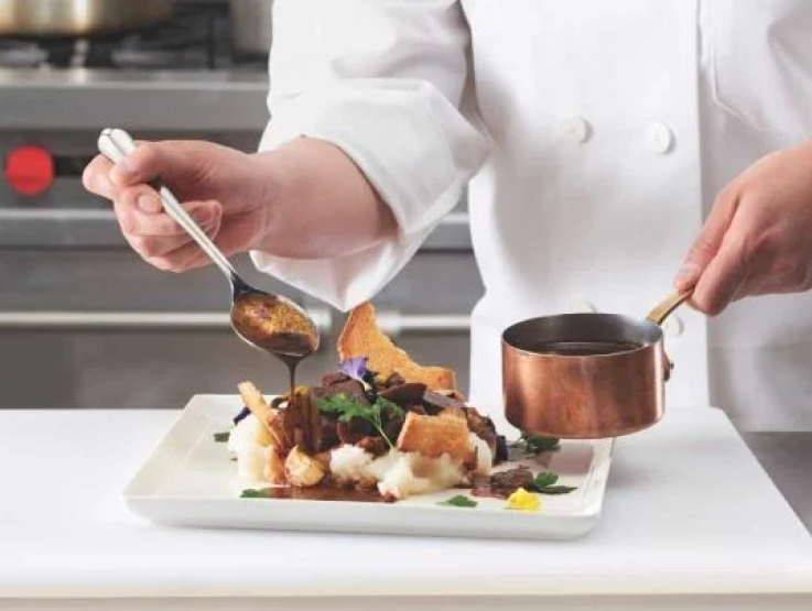 A chef arranges food on a plate, showcasing culinary expertise and creativity in the kitchen.