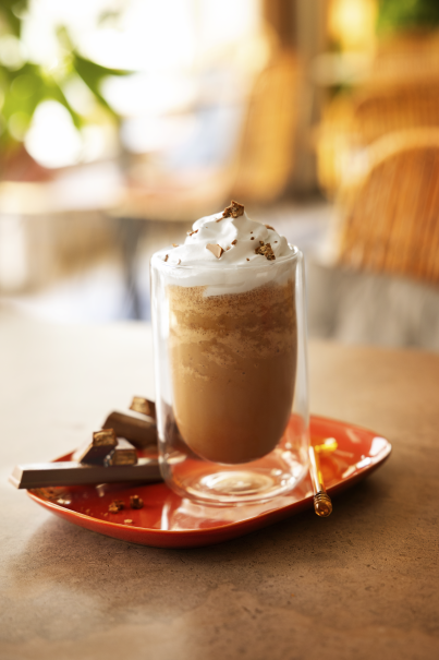 A coffee drink topped with whipped cream and drizzled with chocolate sauce.