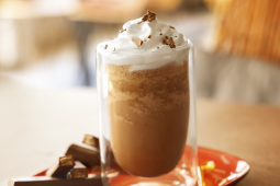 A coffee drink topped with whipped cream and drizzled with chocolate sauce.