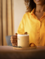 A person enjoys a glass of coffee garnished with cinnamon sticks.