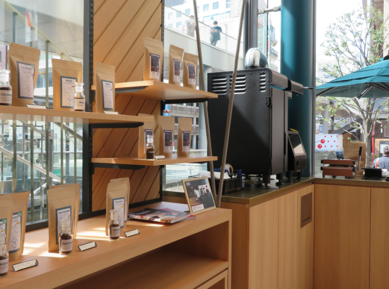 Inside a coffee shop, shelves display an array of coffee and related items, creating an inviting atmosphere.