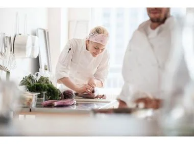 Two chefs collaborating in a kitchen, focused on preparing meals with precision.