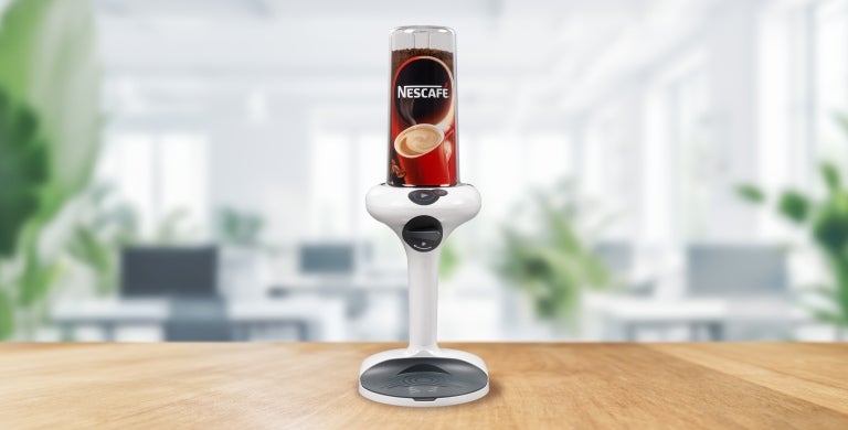 A coffee machine with a steaming cup placed on top, ready for brewing a fresh cup of coffee.